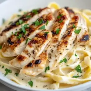 ettuccine Alfredo with grilled chicken, creamy sauce, and parsley garnish, capturing the richness of the dish.